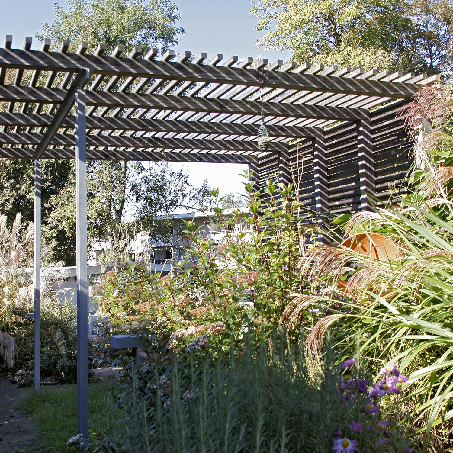 Gartengestaltung eines Reihenhausgartens mit Pergola und verschiedenen Stauden in Esslingen